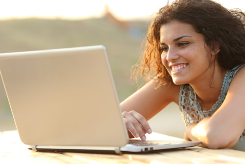 Woman-looking-at-her-laptop-with-a-relaxed-smiling-during-her-Brazilian-Portuguese-and-translations-class